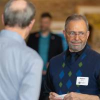 three men chat in hallway